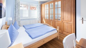 Una camera da letto con un letto in legno, un comodino, una lampada, un armadio e una finestra con persiane.