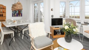 Ein modernes Wohnzimmer mit Essbereich, Fernseher und großem Fenster mit Blick.