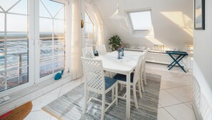 Un espace repas comprenant une table, des chaises et une vue dégagée grâce à de grandes fenêtres.