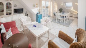 Un salon moderne comprenant un coin repas, des meubles blancs, un téléviseur et une vue sur l’extérieur.