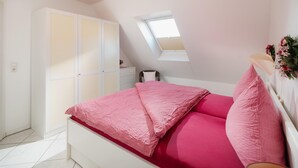 Une chambre à coucher comprenant un lit, une armoire, un bureau, une chaise et une lucarne.