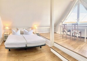 Ein Schlafzimmer mit Bett, Nachttischlampen, einem Fenster und Blick nach draußen.