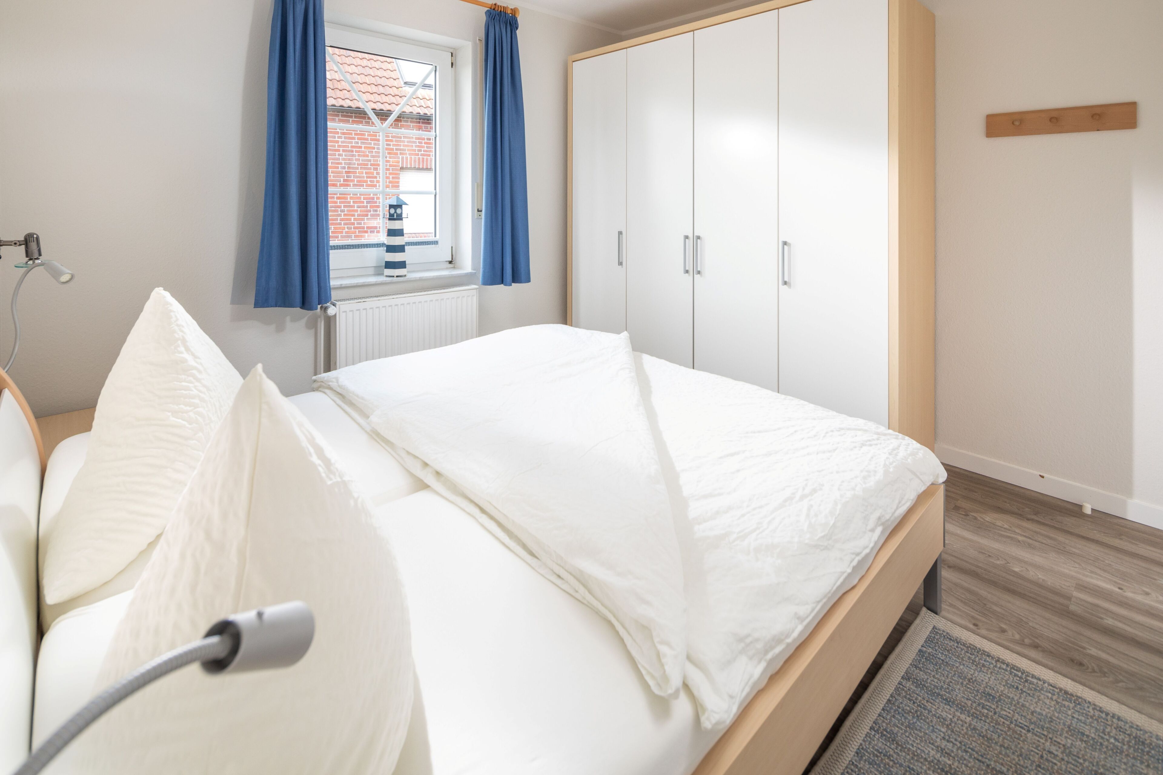Een slaapkamer met een bed, een kledingkast, een radiator en een raam met gordijnen.