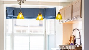 Eine Küche mit Fenster, Spüle und hängenden Pendelleuchten.