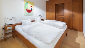 Une chambre avec un grand lit, une armoire en bois et un tableau accroché au mur.