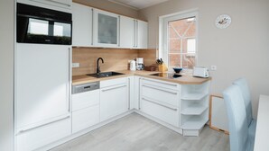 Cocina moderna con armarios blancos, horno empotrado, pileta y ventana con vista.