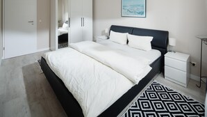 Una habitación de hotel moderna con una cama grande, una mesita de noche, un armario y un cuadro en la pared.