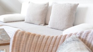 Ein weißes Sofa mit zwei gemusterten Kissen und einem gewebten Sessel.