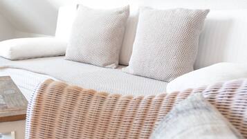 Ein weißes Sofa mit zwei gemusterten Kissen und einem gewebten Sessel.