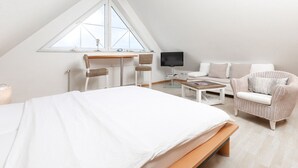 Ein Schlafzimmer mit Bett, Schreibtisch, Sessel, Sofa und Fernseher.
