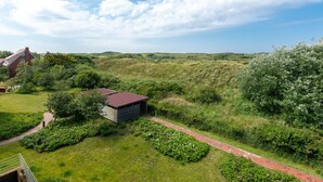 Ländliche Landschaft mit einem kleinen Gebäude, einem Weg und umgebender Vegetation.