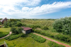 A rural landscape with a small building, a pathway, and surrounding greenery. - Large vacation apartment for 6 people with balcony (Juist)