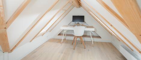 Ein Dachzimmer mit Schreibtisch, Stuhl und Computer.