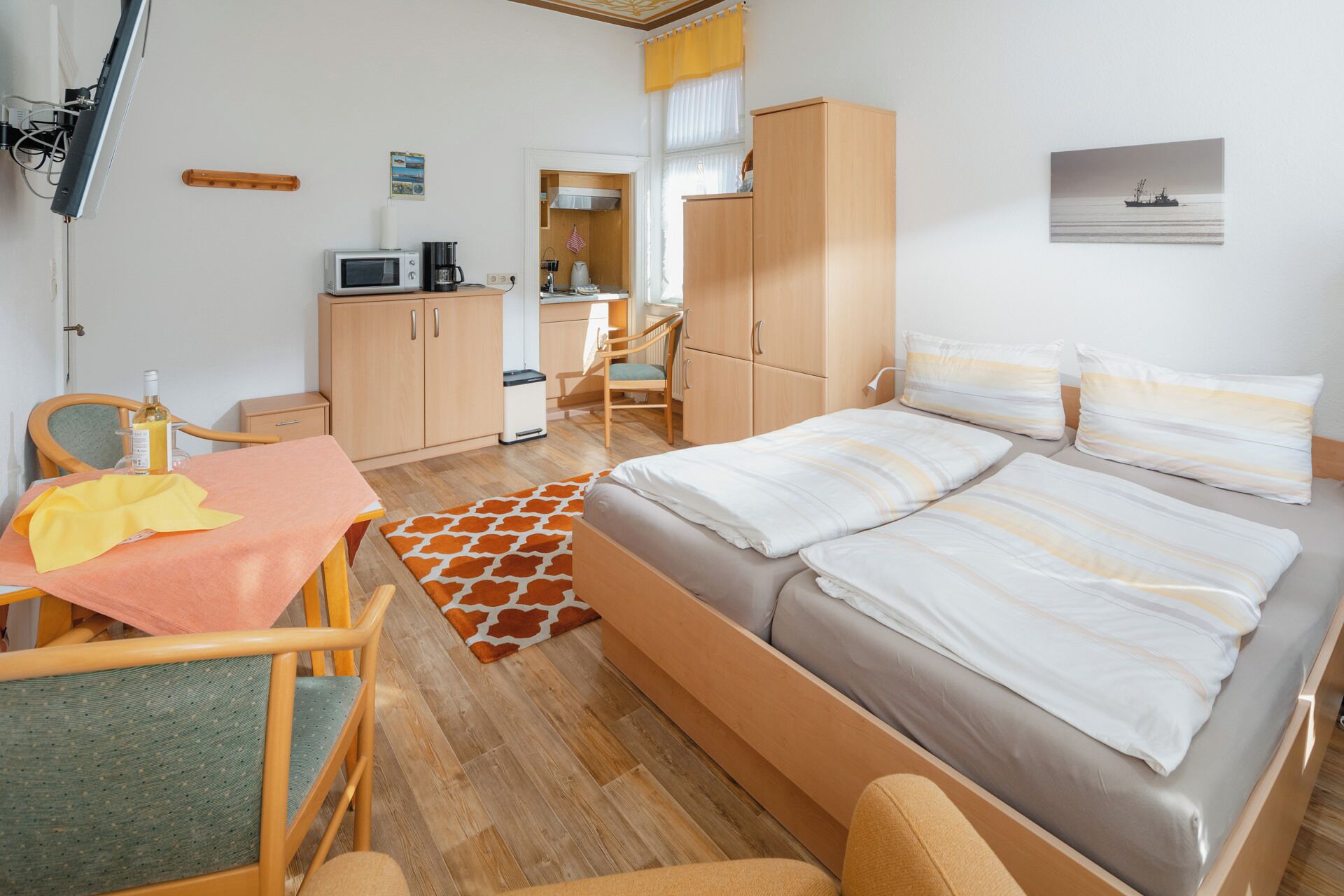 Ein Hotelzimmer mit Bett, Schreibtisch, Stuhl, Mikrowelle, Kaffeemaschine und einem kleinen Schrank.