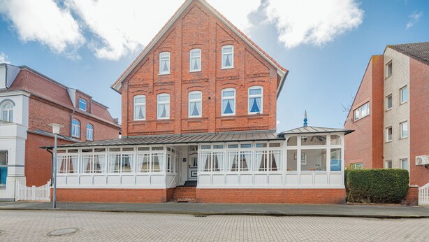 Punatiilinen rakennus, jossa on valkoinen julkisivu, useita ikkunoita ja katettu sisäänkäyntialue.