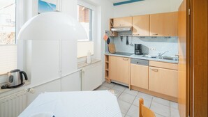 Pieni, käytännöllinen keittiö, jossa on puiset kaapit, työtaso ja ikkuna.