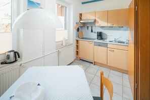 A compact kitchen with wooden cabinets, a countertop, and a window. - Frauke apartment in the Villa Altmanns (Juist)