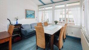 Een zithoek met een tafel en stoelen, een bank en een schilderij aan de muur.