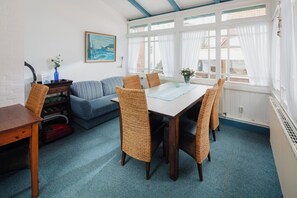 Un coin repas avec une table et des chaises, un canapé et un tableau accroché au mur.