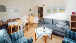 Een woonkamer met een bank, gestreepte stoelen, een eettafel en kunstwerken aan de muren.