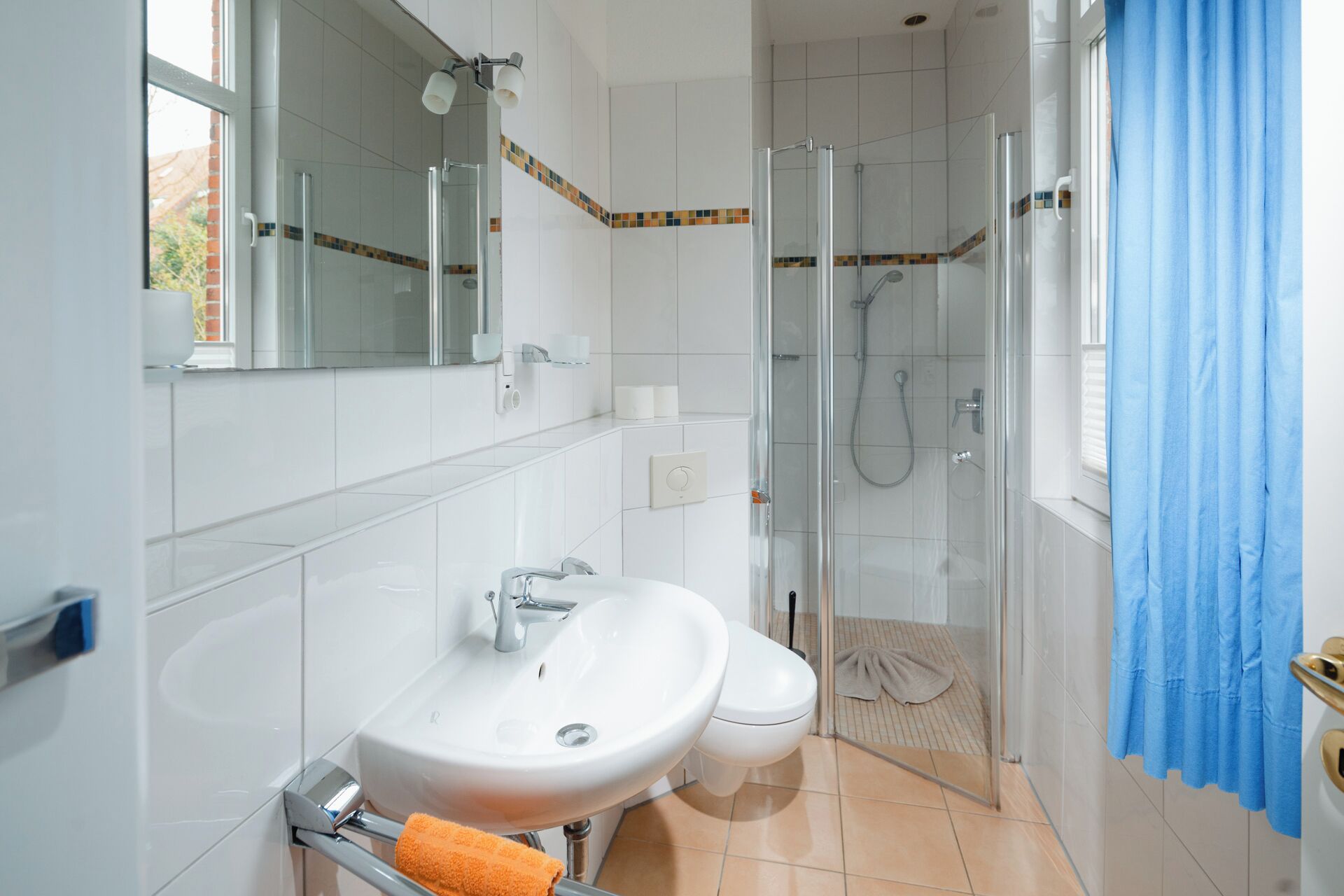 Et badeværelse med vask, toilet, spejl og brusekabine.