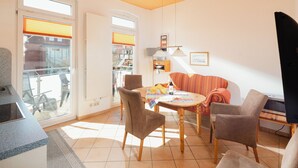 Ein Wohnzimmer mit Esstisch, Stühlen, einer Couch und einem Fernseher.
