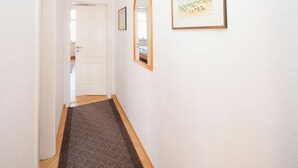 Ein Flur mit Teppich, einer Tür und einem gerahmten Bild an der Wand.