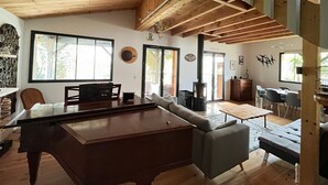 Een ruime woonkamer met biljart, een bank en een eethoek.