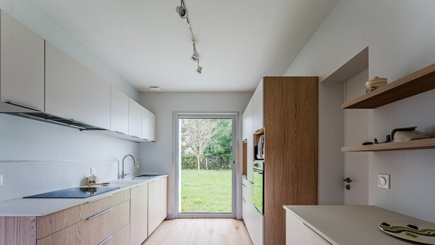 Une cuisine moderne avec des meubles en bois, un four encastré et une vue sur l’extérieur.