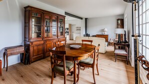 Un vaste espace dédié à la salle  à manger, avec une table et des chaises en bois, un grand meuble en bois, et une vue sur la cuisine et le salon.