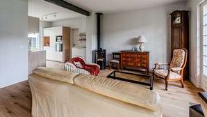 Un salon avec un canapé, un meuble en bois, un fauteuil et une cheminée.