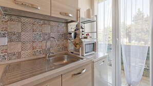 A modern kitchen with patterned tiles, a stainless steel sink, and a microwave. - Holiday Home Villanova (Villanova)