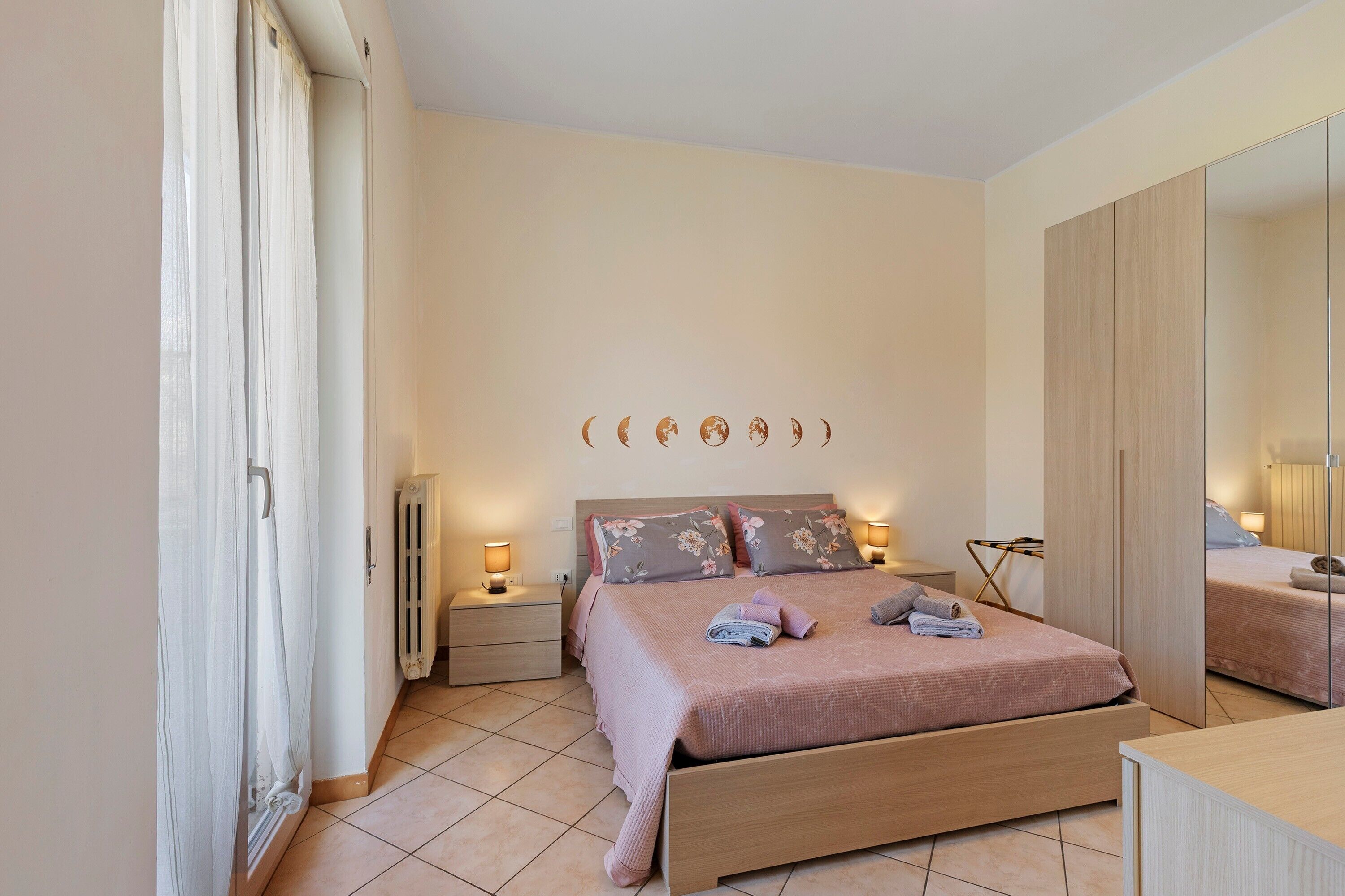 A bedroom with a bed, bedside tables, a mirror, and a radiator.