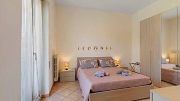 A bedroom with a bed, bedside tables, a mirror, and a radiator.