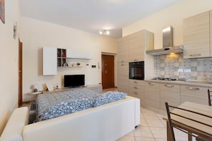 A compact room with a bed, a TV, a kitchenette, and a small dining area.
