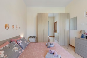 A bedroom with a bed, a dresser, a mirror, and a door leading to another room.