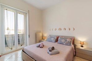 Une chambre à coucher comprenant un lit, deux tables de chevet, une commode, une fenêtre avec des rideaux et un mur décoré avec les différentes phases de la lune.