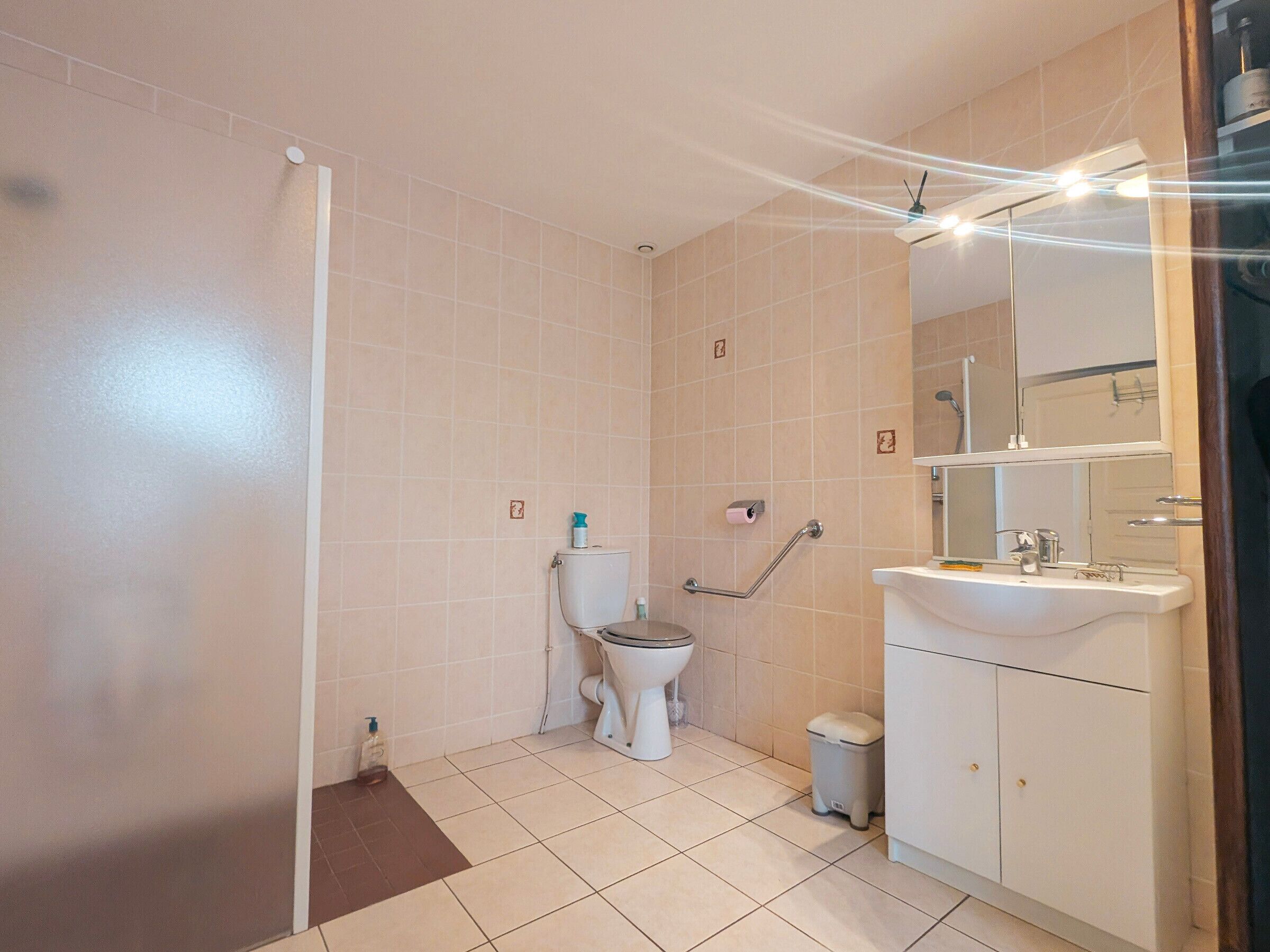 Une salle de bain équipée de toilettes, d’un bidet, d’un lavabo et d’un miroir.