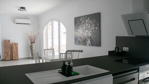 Een moderne keuken met een witte spoelbak, roestvrijstalen apparatuur en een groot raam.