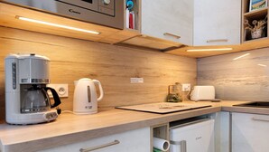 A kitchen with a coffee maker, toaster, and a cabinet with a sign. - Duplex in Carolles, Bay of Mont Saint Michel, 50 m from the Beach (Carolles)