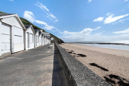 A row of white beachside cottages with a paved walkway leading to the beach.. Duplex in Carolles, Mont Saint Michel Bay, 50 m from the Beach