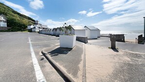 A coastal road with white buildings, a parking area, and a view of the sea. - Duplex in Carolles, Bay of Mont Saint Michel, 50 m from the Beach (Carolles)