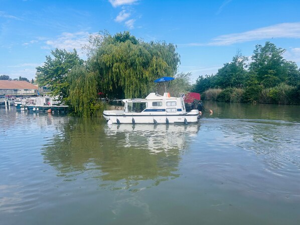 A small boat docked at a calm river with a weeping willow tree in the background. - Docked boat with kitchenette - 4 guests (Colombiers)
