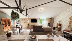 Un vaste espace de vie comprenant une table à manger, un canapé et un coin cuisine équipé d’une cuisinière.