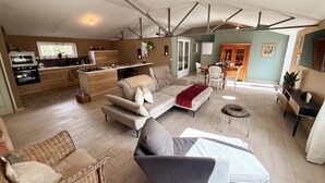 Un grand espace de vie comprenant un canapé, des fauteuils, une table à manger et une cuisine à l’arrière-plan.