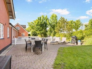 A patio area with a table and chairs, a barbecue grill, and a white picket fence. - 4 Star Holiday Home in Hjorring (Hjørring)