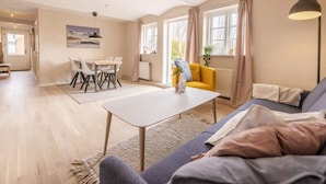 A spacious living area with a dining table, sofa, and a view of the outdoors. - 4 Star Holiday Home in Hjorring (Hjørring)