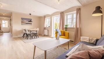 A spacious living area with a dining table, sofa, and a view of the outdoors.