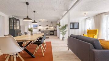 A modern open-plan living space with a dining area, kitchen, and seating area.