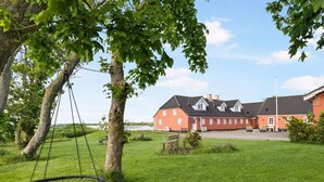A red building with a white fence, a swing, and a grassy field. - 4 Star Holiday Home in Hjorring (Hjørring)